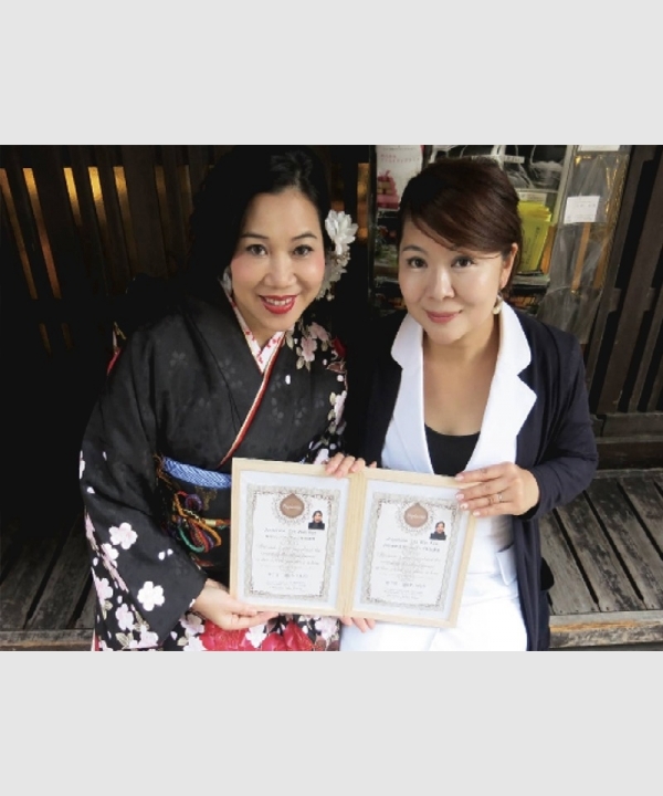 創辦人與穿黑色和服女士展示兩張證書